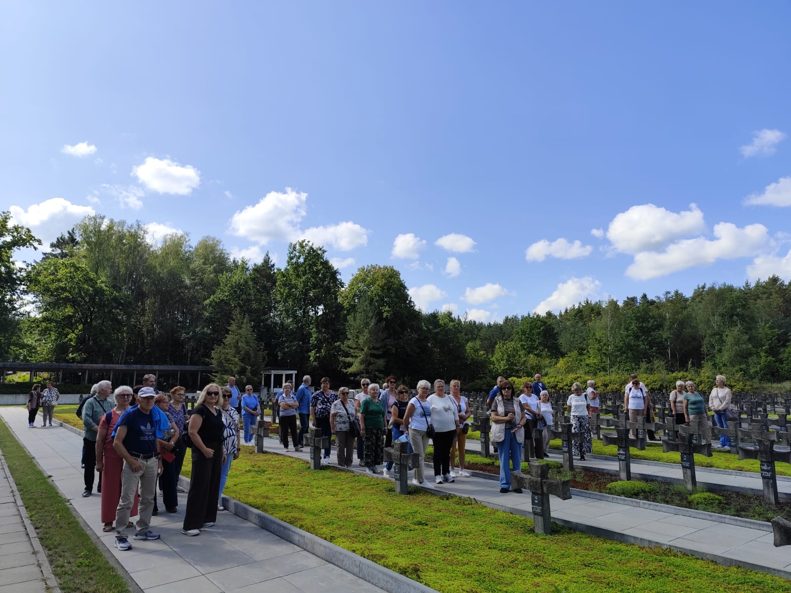 Zdjęcie grupowe, wykonane w pozycji horyzontalnej, przedstawiające seniorów na tle lasu