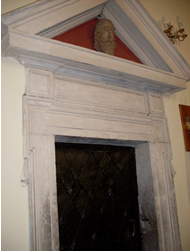 Kamienny portal z ozdobnymi drzwiami  i rzeźbą głową św. Jana Chrzciciela  w tympanonie  (pamiątka z dawnego kościoła)